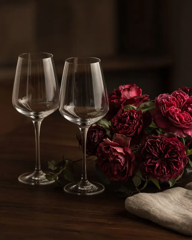 Two glasses and a low arrangement of deep red roses